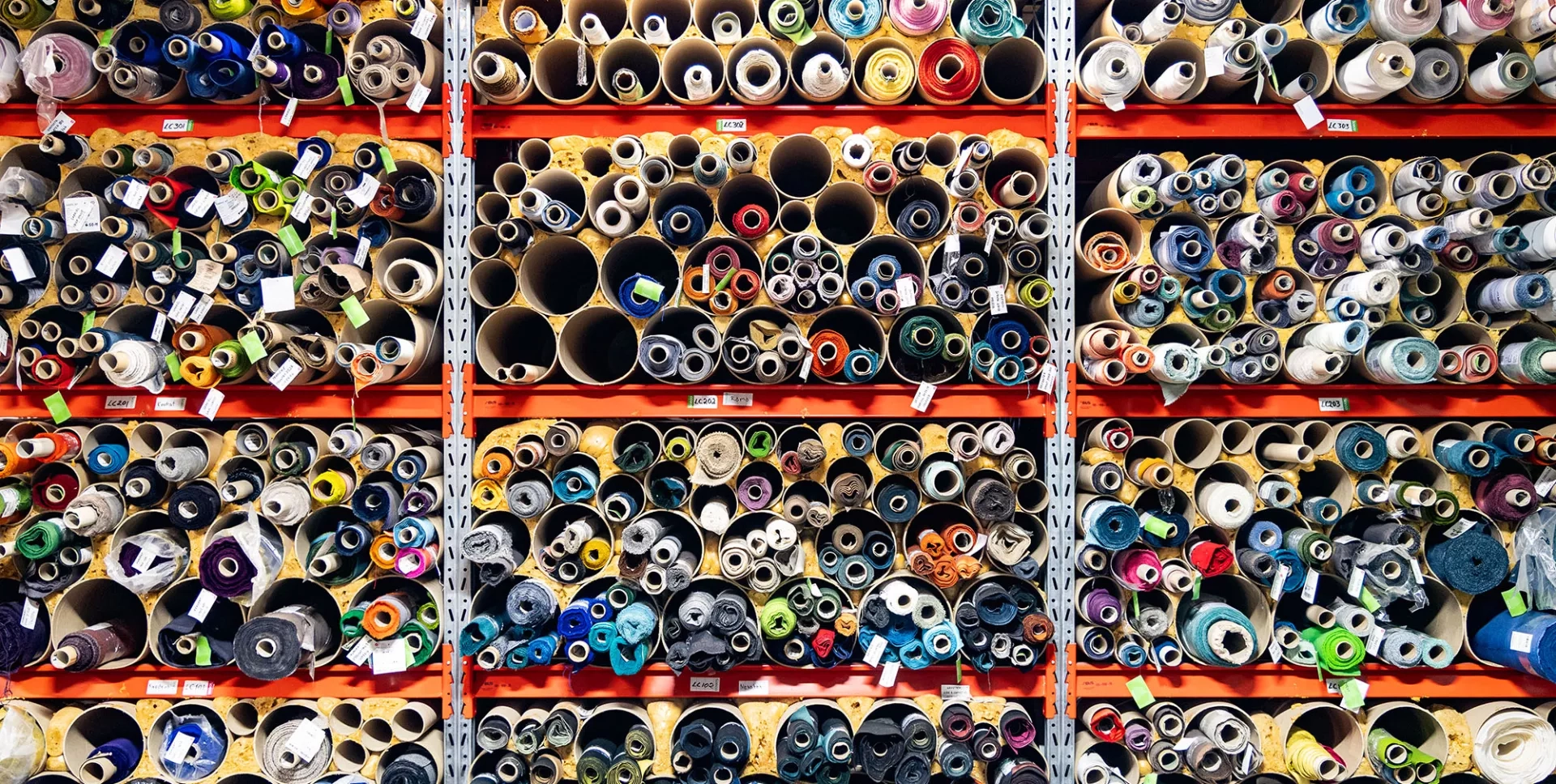 Vägg med tygrullar i mängder av olika färger i Yllw Factorys tapetseri