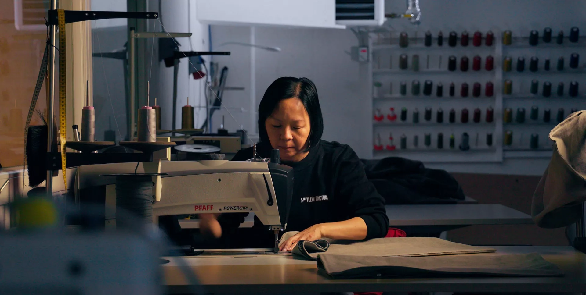 Sömmerska syr vid en symaskin på Yllw Factory
